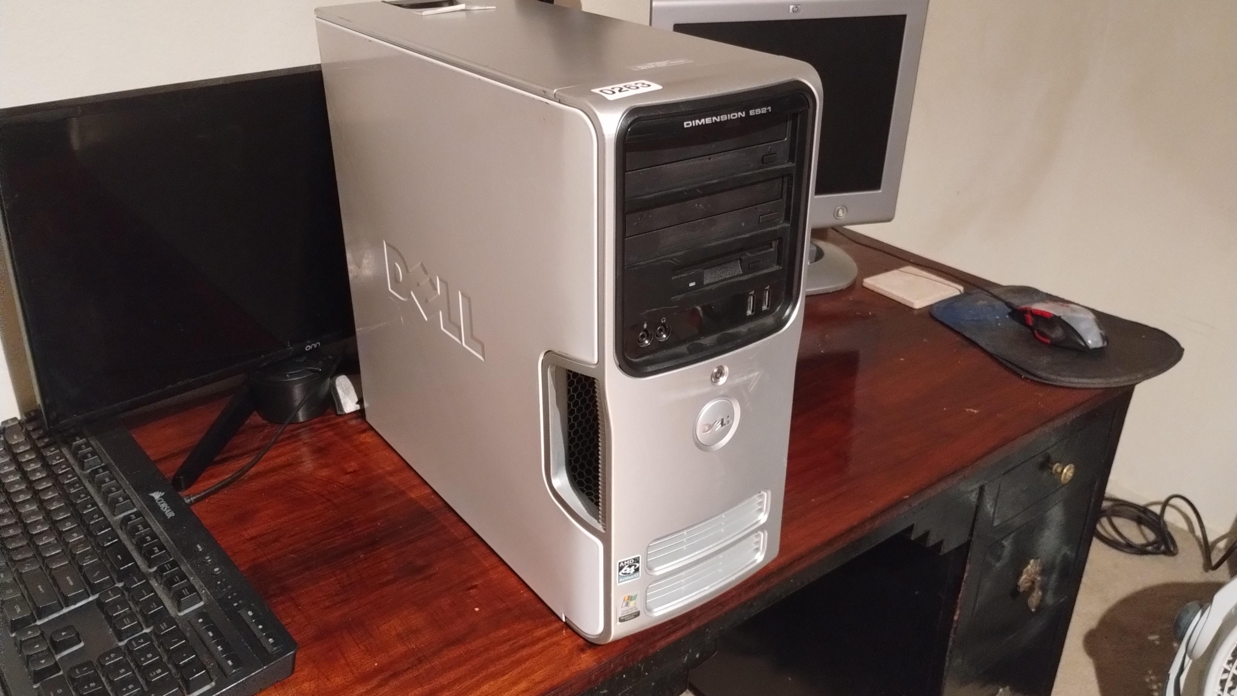 A clean silver and white Dell Dimension E521 sitting on a wooden desk.