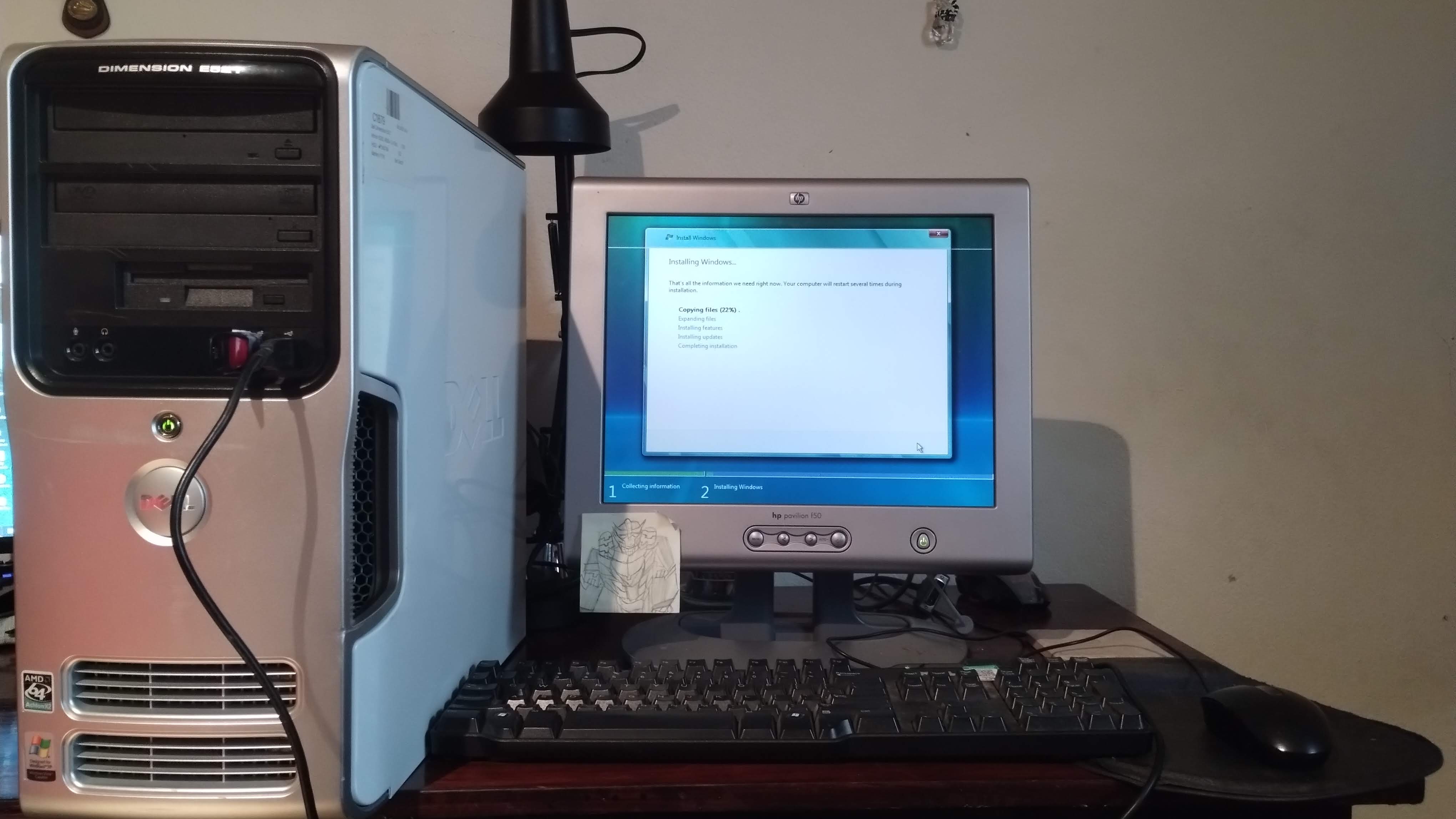 A screen of the Windows Vista install program, with a wide angle shot to show the computer case and keyboard and mouse.