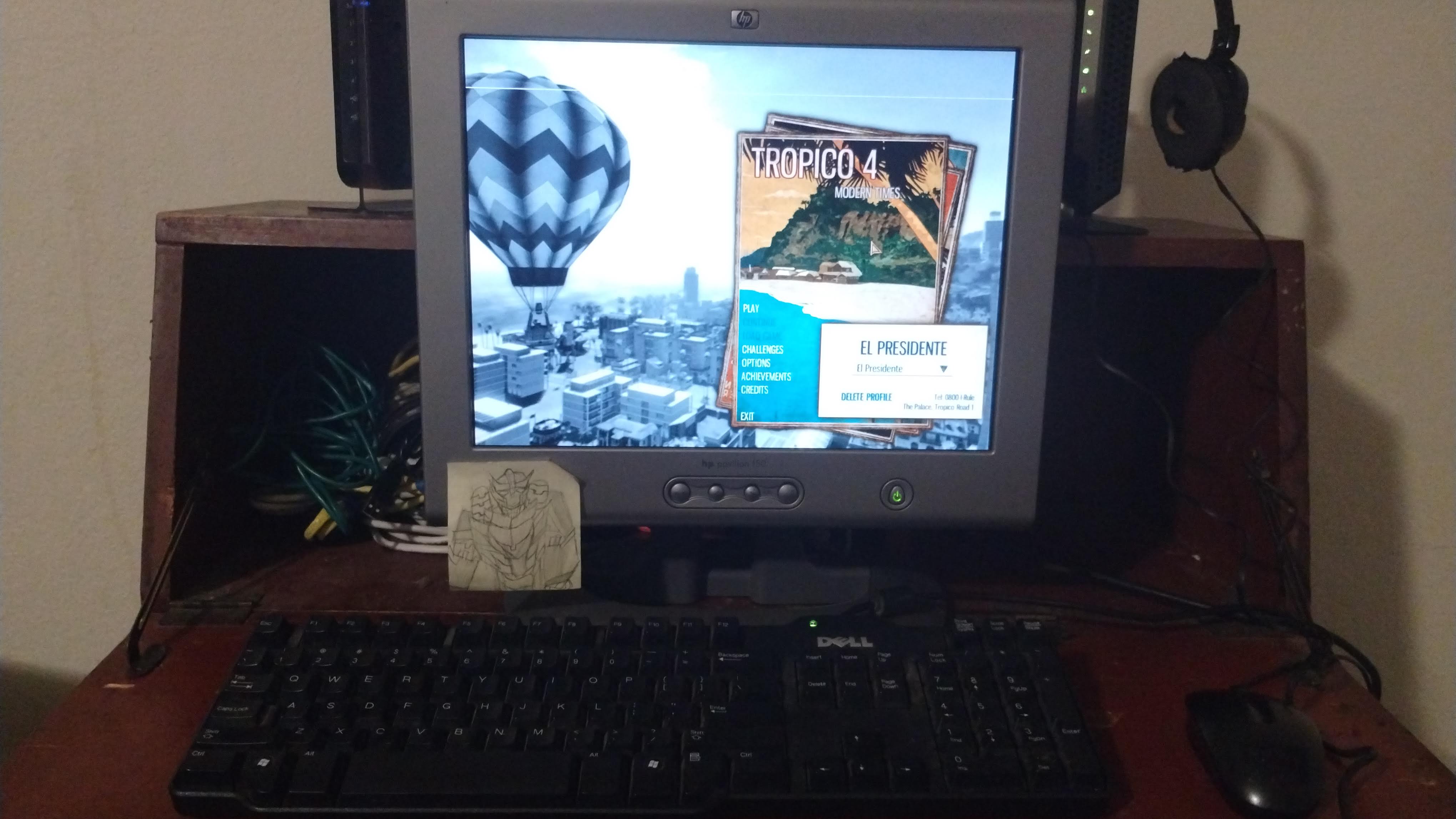 An old monitor sitting on a desk displaying the menu screen for Tropico 4