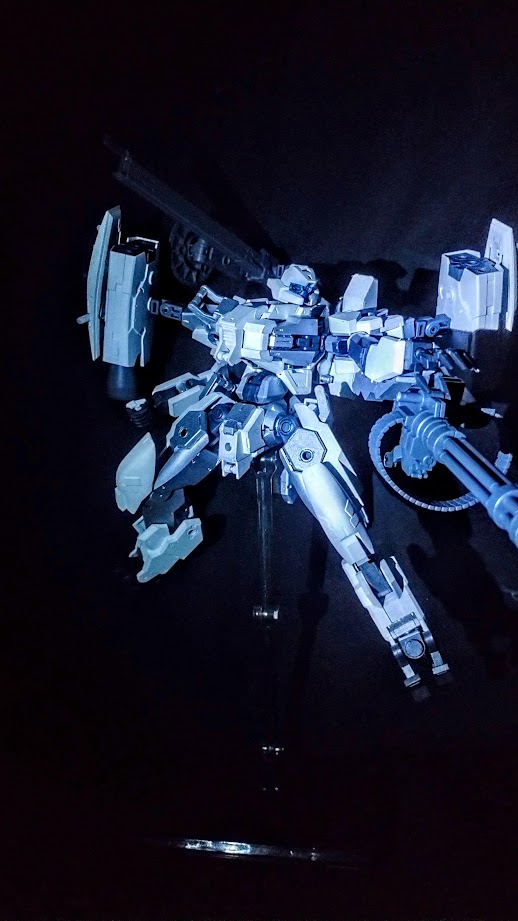 Another picture of the same model in a dynamic pose, its cannon pointed outward and its railgun raised. The model kit is pictured against a dark black backdrop.