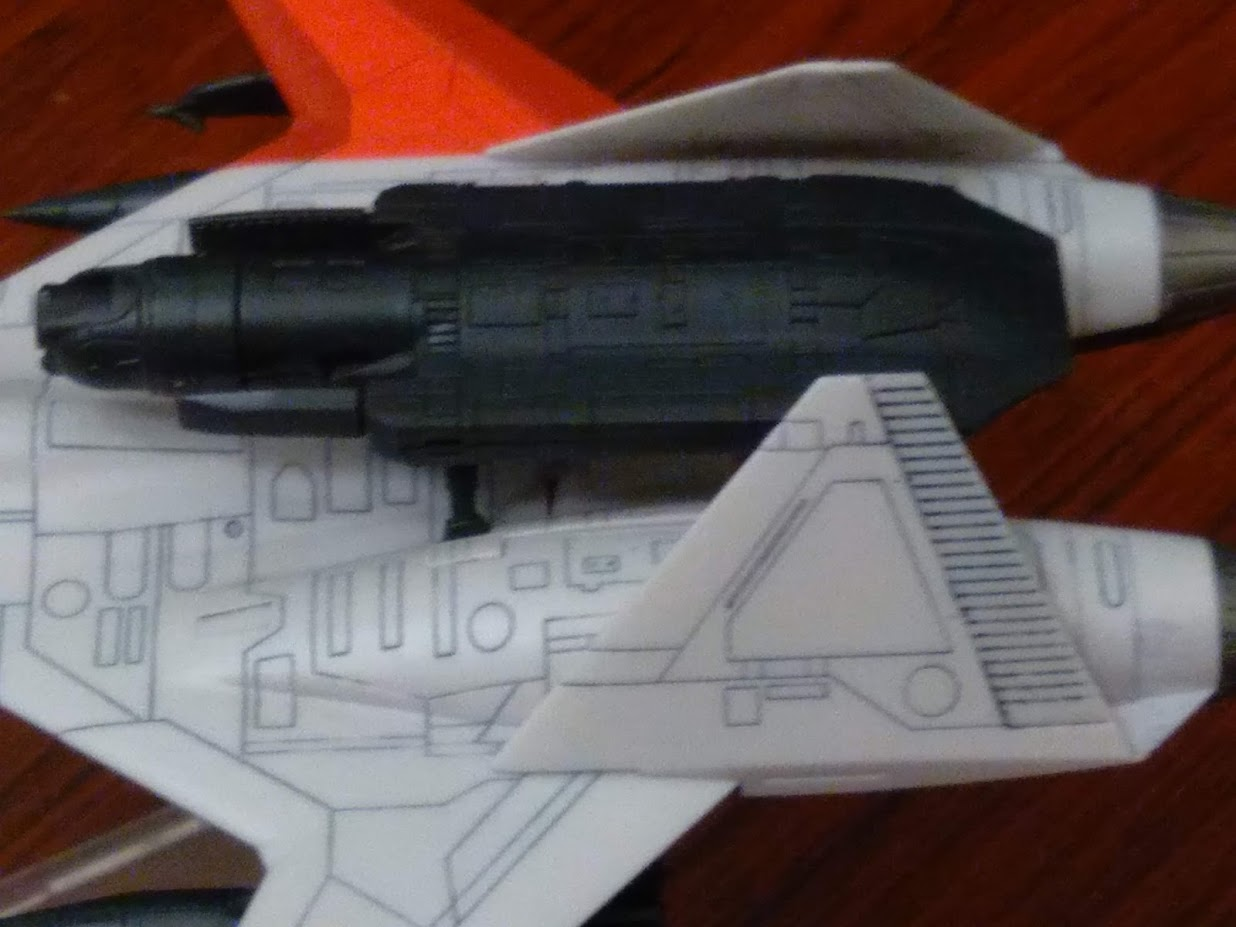 A model kit of a 1/144 ADFX-01 from Ace Combat Zero sitting on a desk. The photo is focusing on the top mounted laser cannon and the texture of its rear fins.