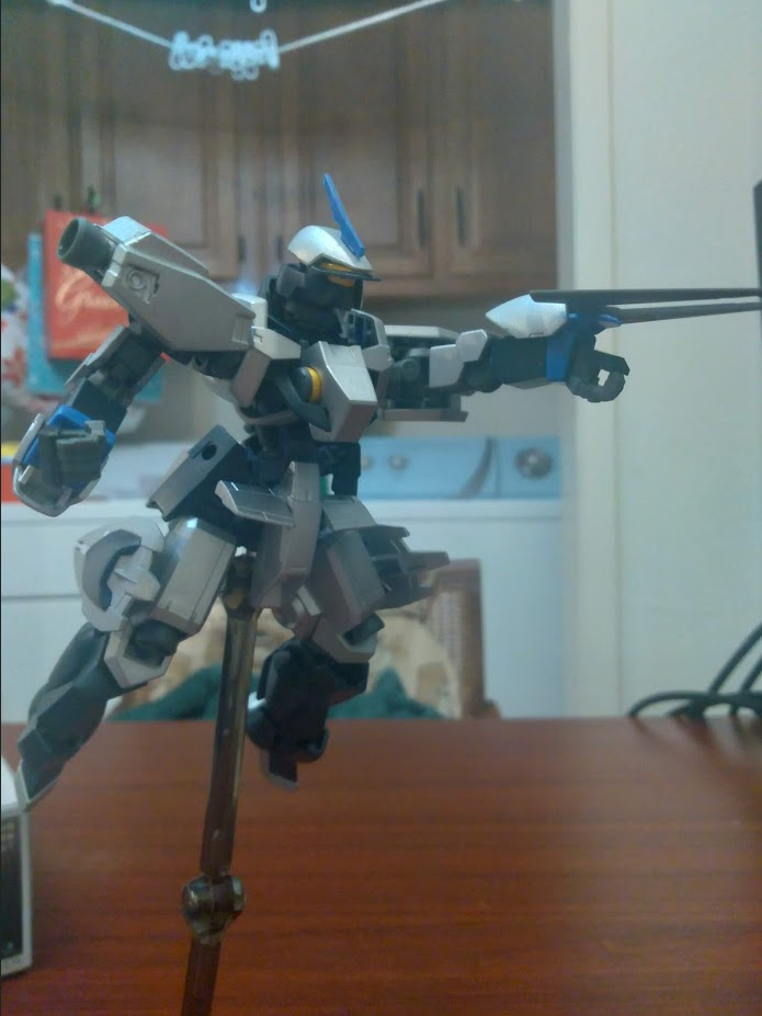 A model kit of a Schwalbe Graze from Gundam IBO mounted on a stand. The figure is posed to appear as though it is in flight, with its left arm held out at a straight 90 degree angle and a grapple claw mounted on its wrist.